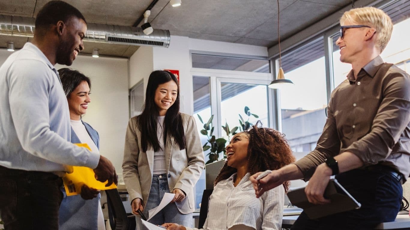 Diverse professionals laughing together in a sunlit workspace